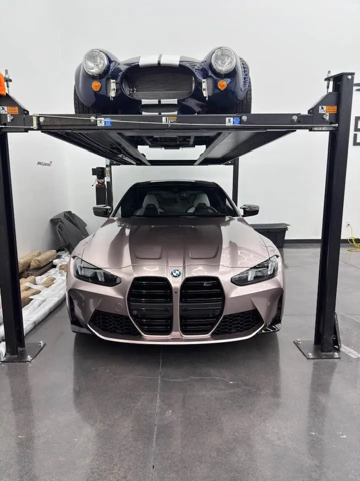 Shelby Cobra raised on a four-post lift above a BMW M4 inside a Gateway Storage vehicle bay